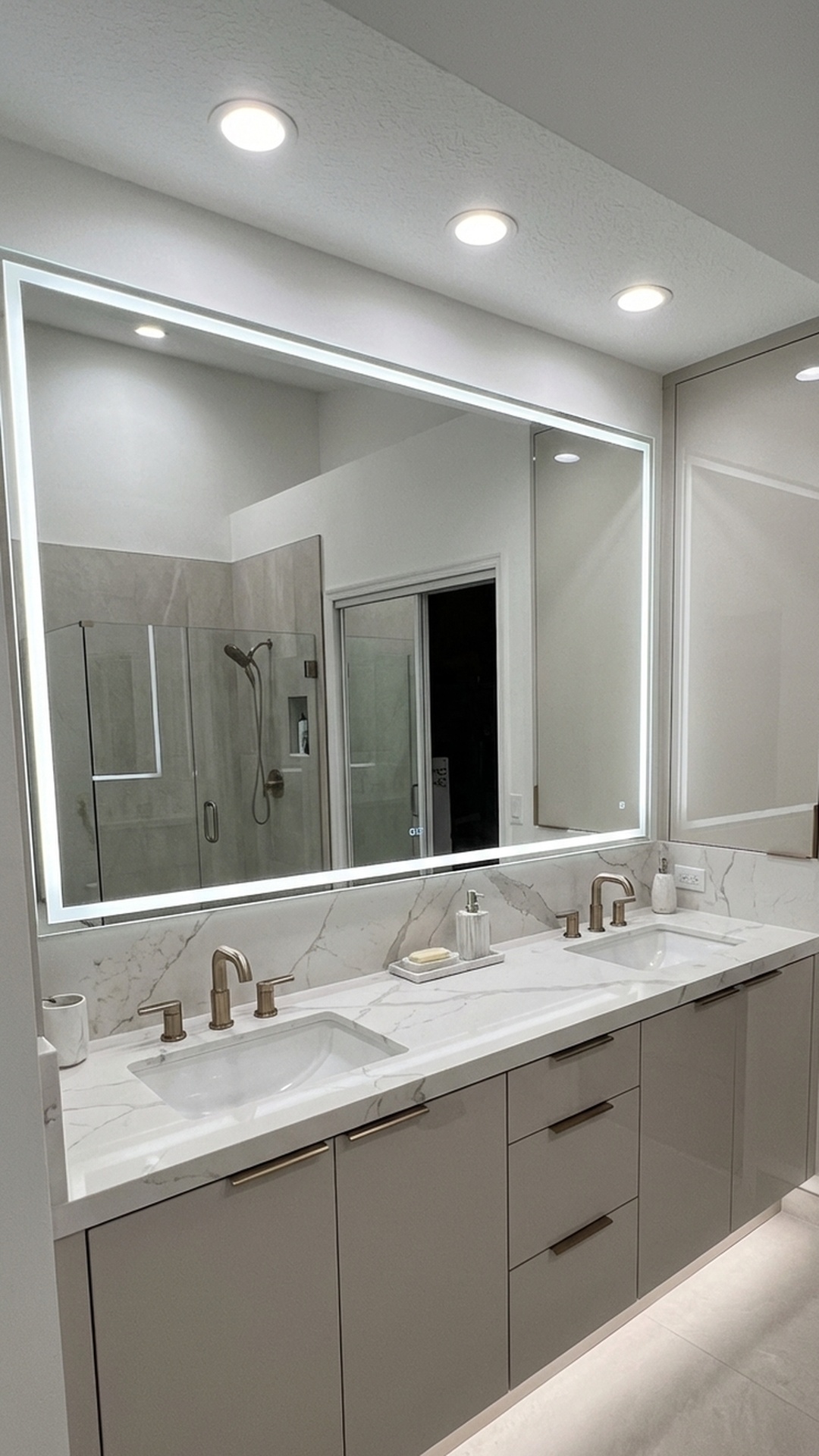 Modern bathroom remodel in Jupiter, FL with backlit vanity mirror, marble countertop, and glass walk-in shower by MELTINI Remodeling